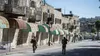 Two Israeli soldiers patrol past shuttered Palestinian shops on Shuhada Street in Hebron