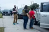 ICE ERO and HSI officers stand beside a handcuffed man at a roadside stop in San Antonio