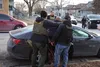 Two ICE officers in POLICE vests handcuff a man against a car during a vehicle stop in Chicago in January 2025