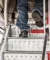 A deportee with a chain between his ankles climbs the steps of an ICE removal flight