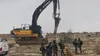 Israeli forces stand by an excavator demolishing Palestinian homes