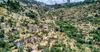The stone houses of Lifta on terraced slopes, with Jerusalem's high-rise buildings above the valley