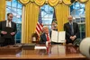 Will Scharf holds a folder as Donald Trump signs executive orders in the Oval Office