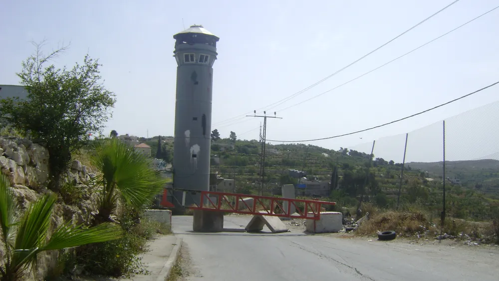 A closed Israeli gate and watchtower on the road into Beit Ommar