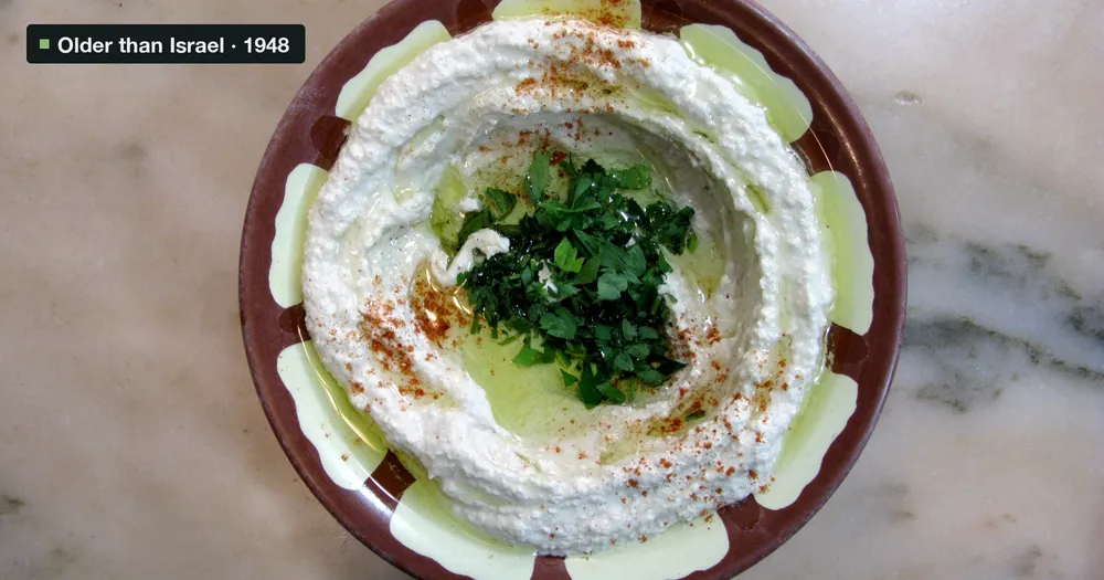 A bowl of hummus with olive oil, paprika and parsley on a marble table in Baalbek, Lebanon