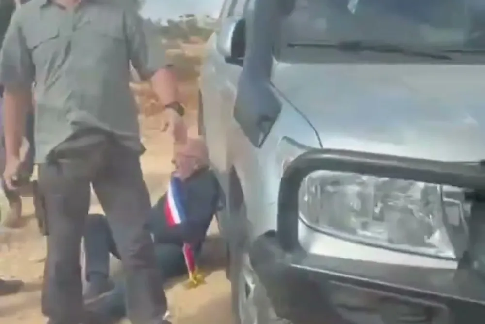 The French mayor Bernard Baudoux on the ground beside a consular vehicle in Taybeh as a man stands over him, 17 October 2026
