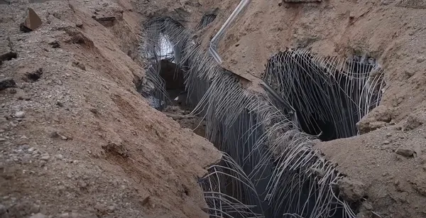 A crater where the Qasmiyeh bridge over the Litani river stood, with bent steel rods hanging into the gap