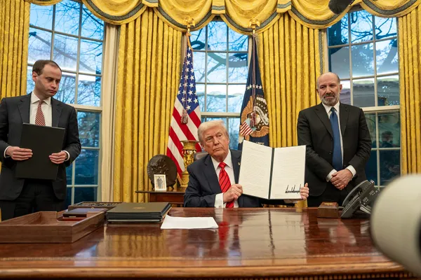 Will Scharf holds a folder as Donald Trump signs executive orders in the Oval Office
